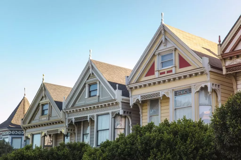 The Painted Ladies of San Francisco - a row of colorful Victorian houses with their distinctive architecture and ornate details, framed by green shrubbery against a blue sky.